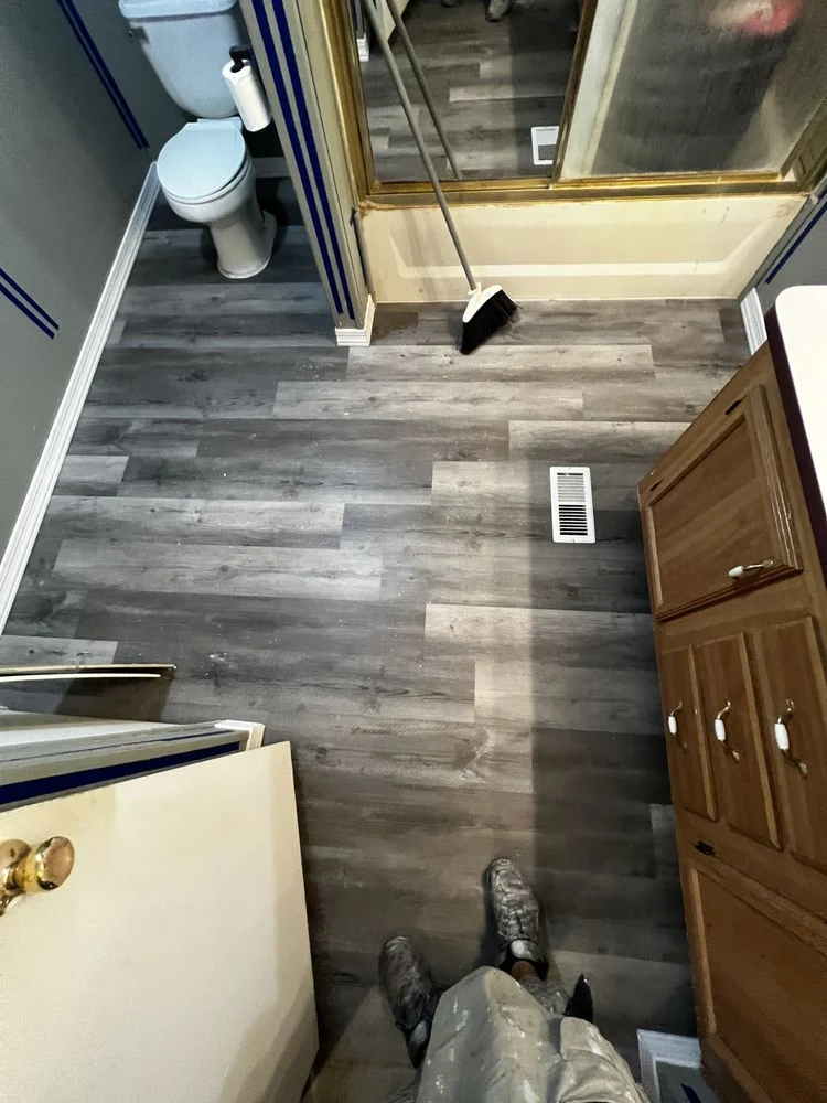 Newly installed gray wood-look vinyl plank flooring in a bathroom