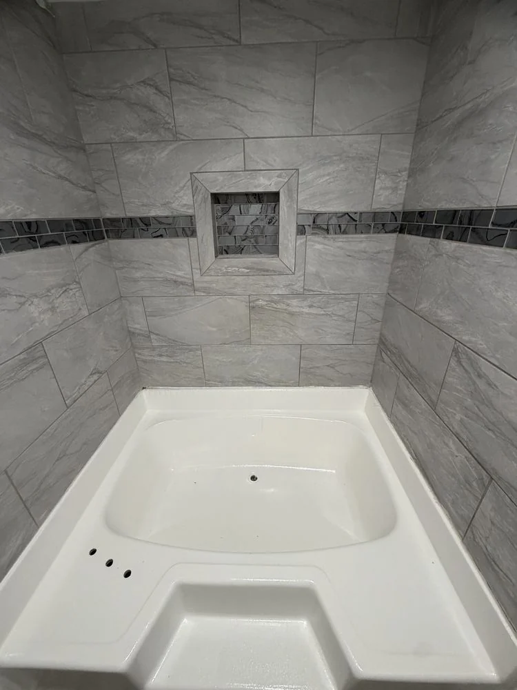 Completed tiled shower with a recessed niche and decorative tile band