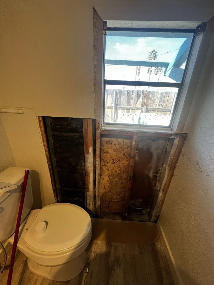 Bathroom wall opened below a window to repair damaged framing and sheathing